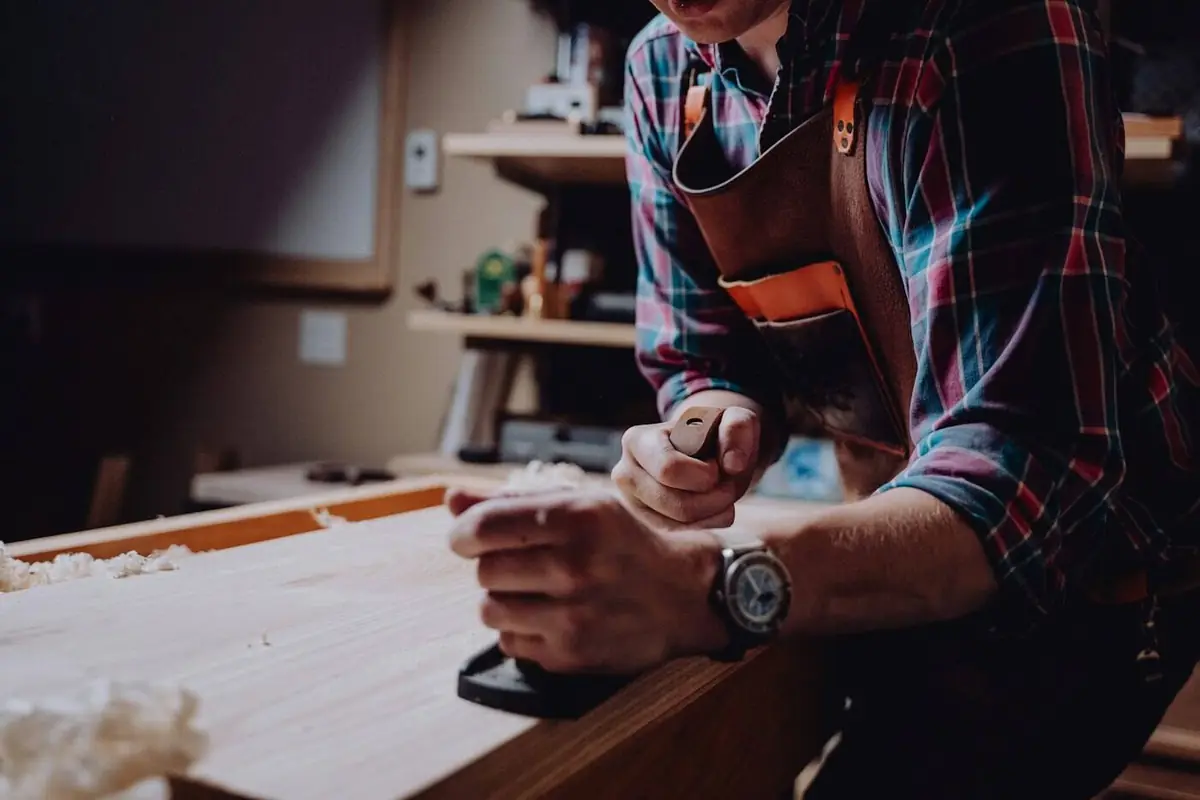 A woodworker in a leather apron planing a board